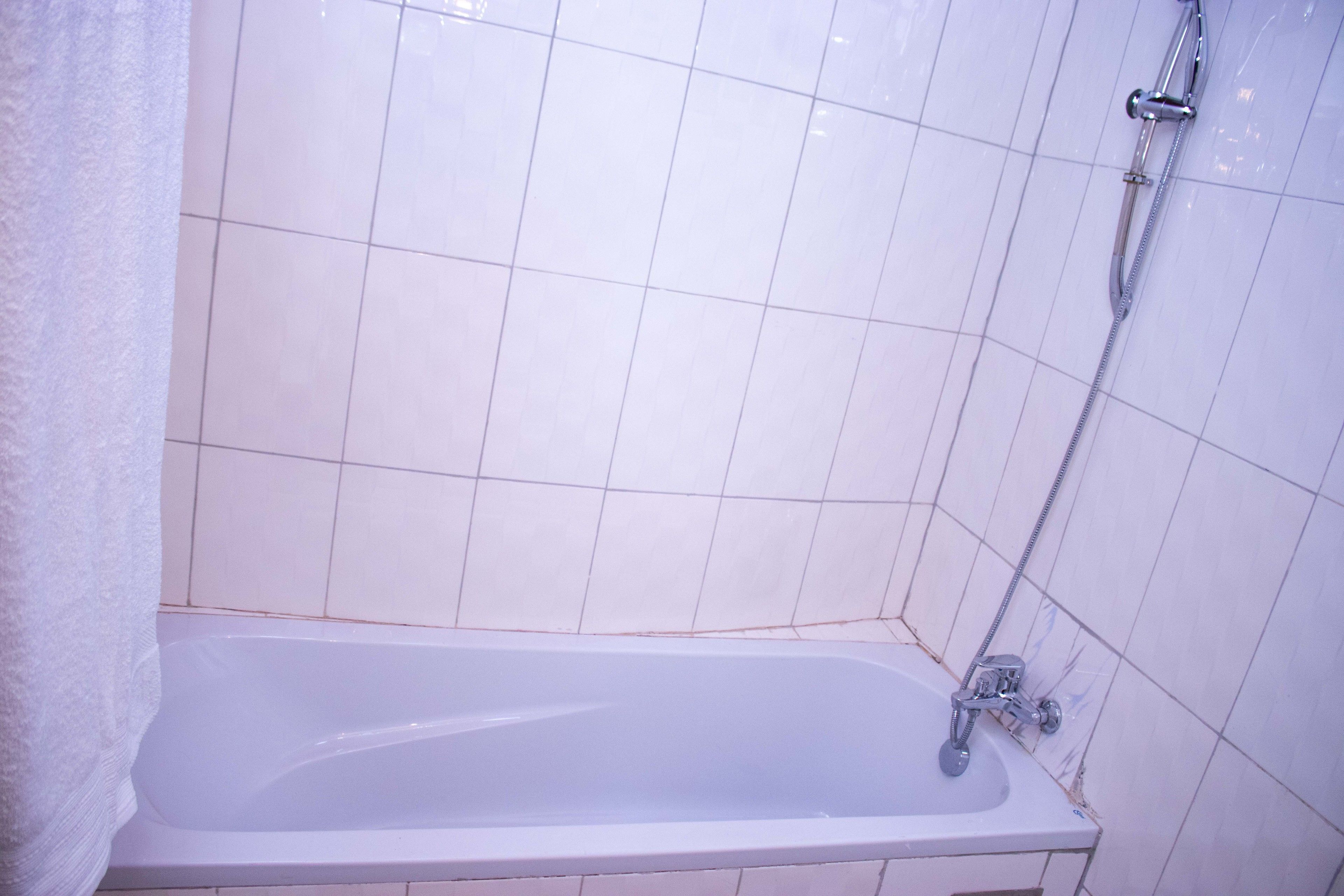 Een badkamer met een bad, een douche en betegelde wanden.