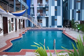 A swimming pool with a tiled edge, a staircase leading to an upper level, and a balcony with a railing. - Odjidja Royal Palace Hotel (Taifa)