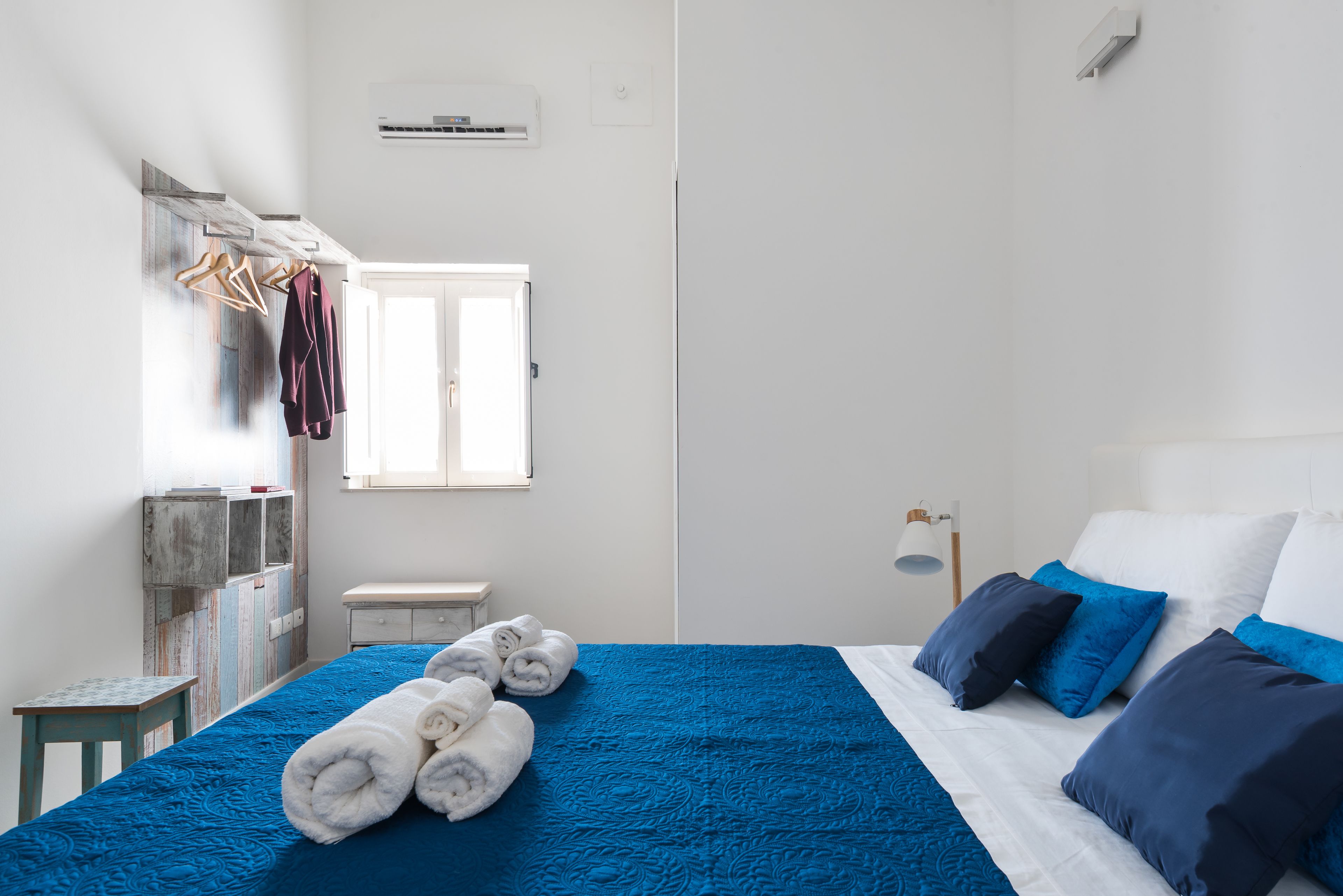 Een slaapkamer met een bed, een raam, een kast en een klein tafeltje.