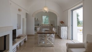 Eine geräumige Küche mit gewölbter Decke, einem Esstisch und einem großen Fenster.