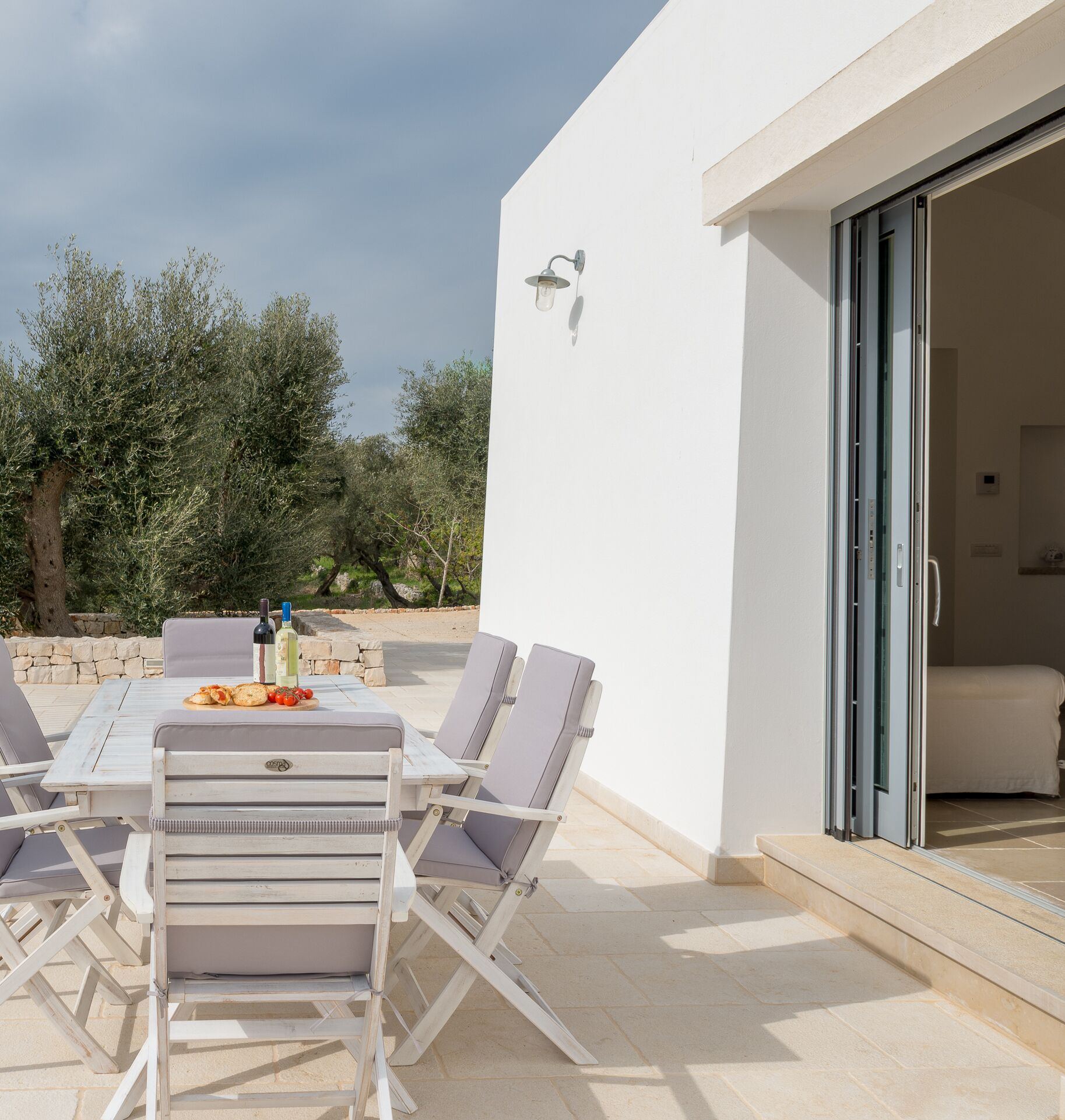 An outdoor patio with a table set for two, surrounded by lounge chairs.