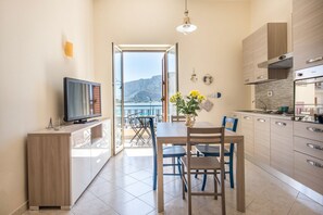 A modern kitchen with a dining area, a TV, and a view of the sea. - Casetta Vista Mare in Piazza a Mondello by Wonderful Italy (Palermo)