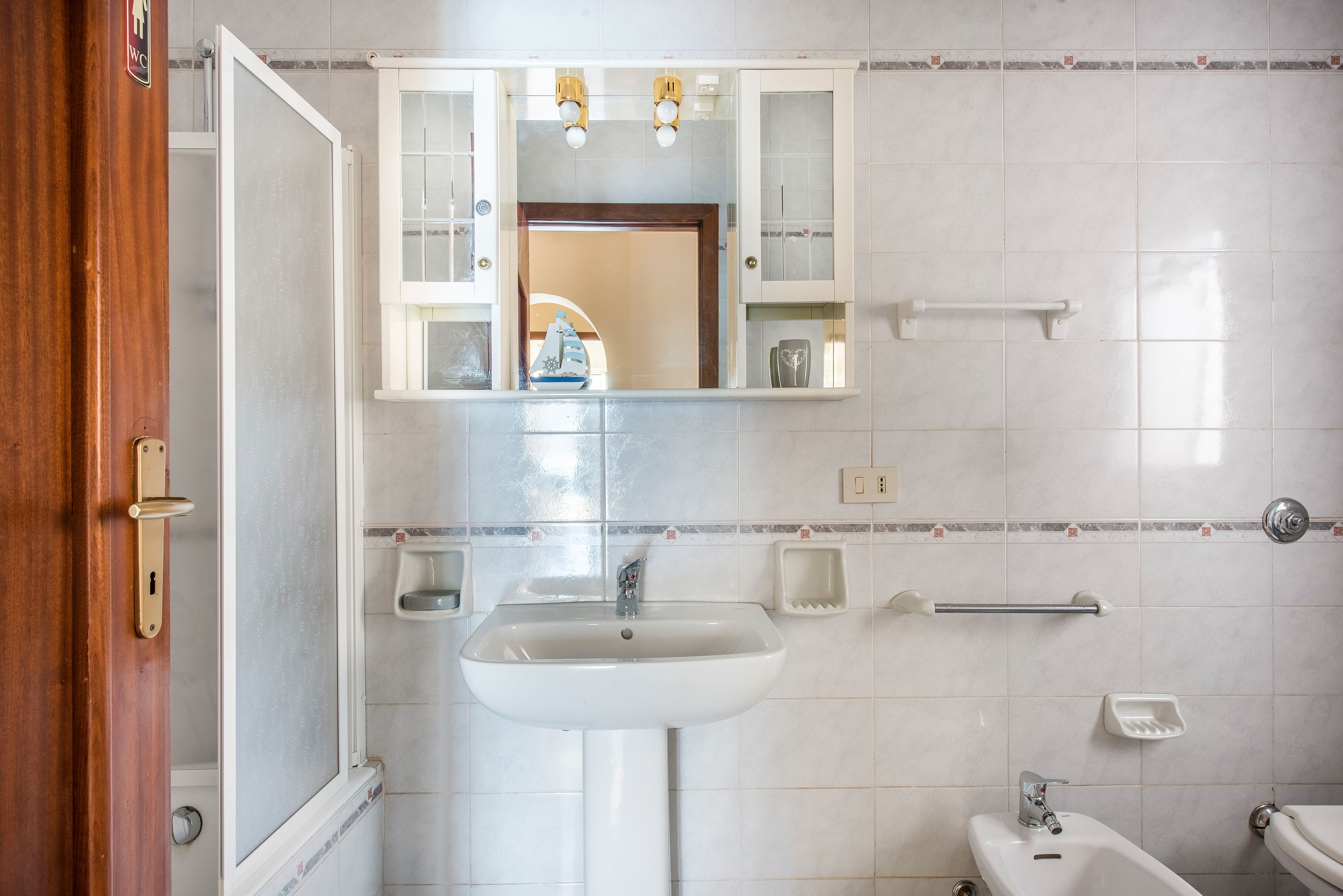 Un baño con un lavamanos blanco, un espejo encima y un inodoro.