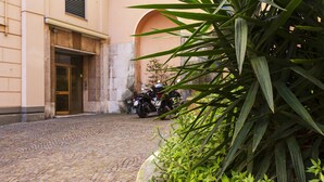 Un patio empedrado con una motocicleta estacionada cerca de la entrada de un edificio.