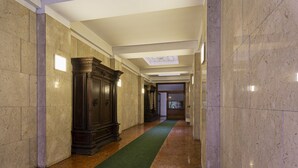 Un pasillo con paredes de mármol, una alfombra verde y un gran armario de madera.