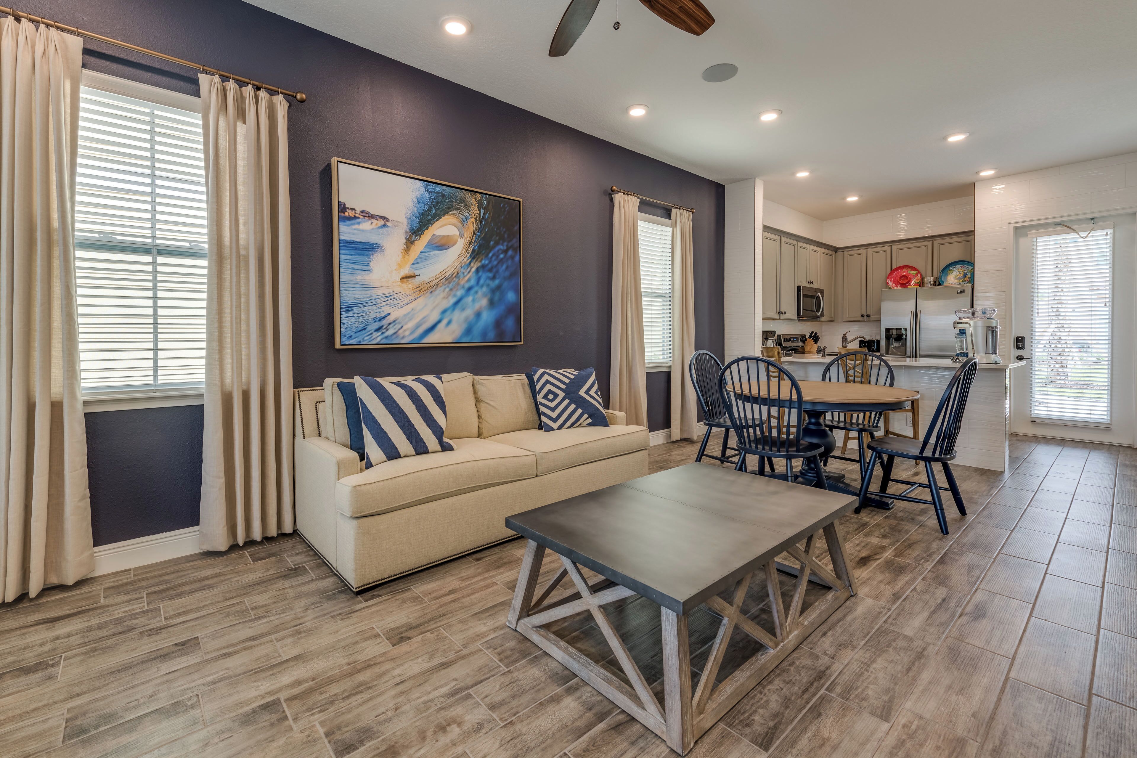 A modern living room with a beige sofa, a wooden coffee table, and a dining area with a wooden table and chairs.