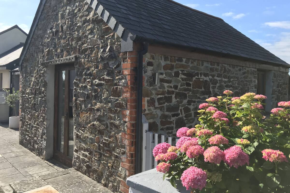 Un bâtiment en pierre avec un toit en pente et une porte.