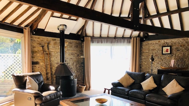 A cozy living room with stone walls, a fireplace, leather sofas, and a glass coffee table.