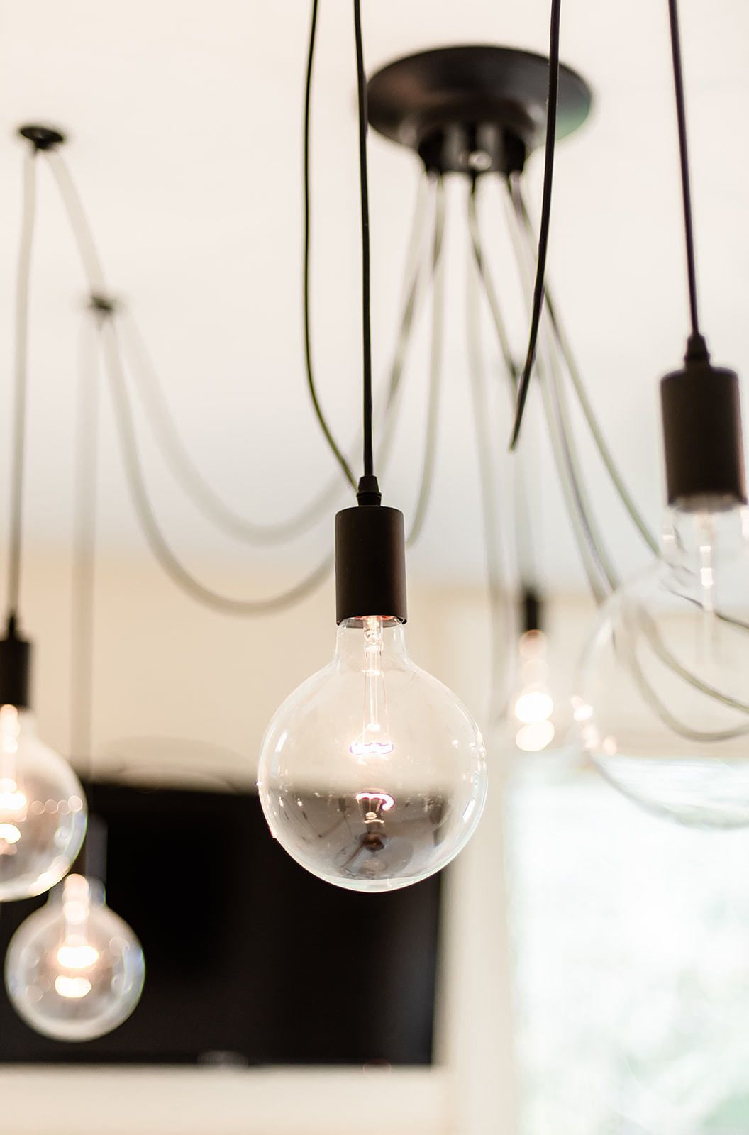 A chandelier with multiple clear glass bulbs and black fixtures.