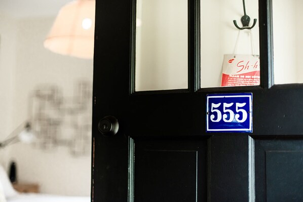 Una puerta negra con un letrero azul que indica el número 555.