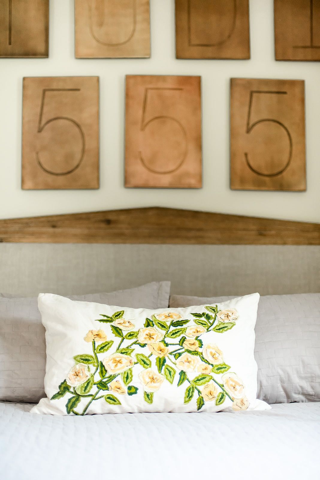 A bedroom with a bed, pillows, and a wall with wooden numbers.