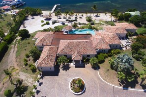 An aerial view of a resort with multiple buildings, a swimming pool, and a beach area.