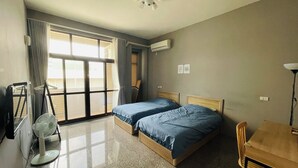 Una camera d'albergo con due letti, una ventola a soffitto, una scrivania e una sedia.