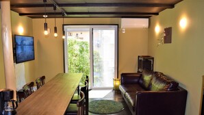 A dining area with a wooden table and chairs, a sofa, and a television on the wall. - Itomori (Takayama)