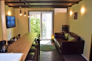 Un comedor con una mesa y sillas de madera, un sofá y un televisor en la pared.