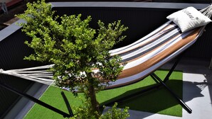 A hammock with a striped fabric, a white pillow with text, and a tree in the background. - Itomori (Takayama)