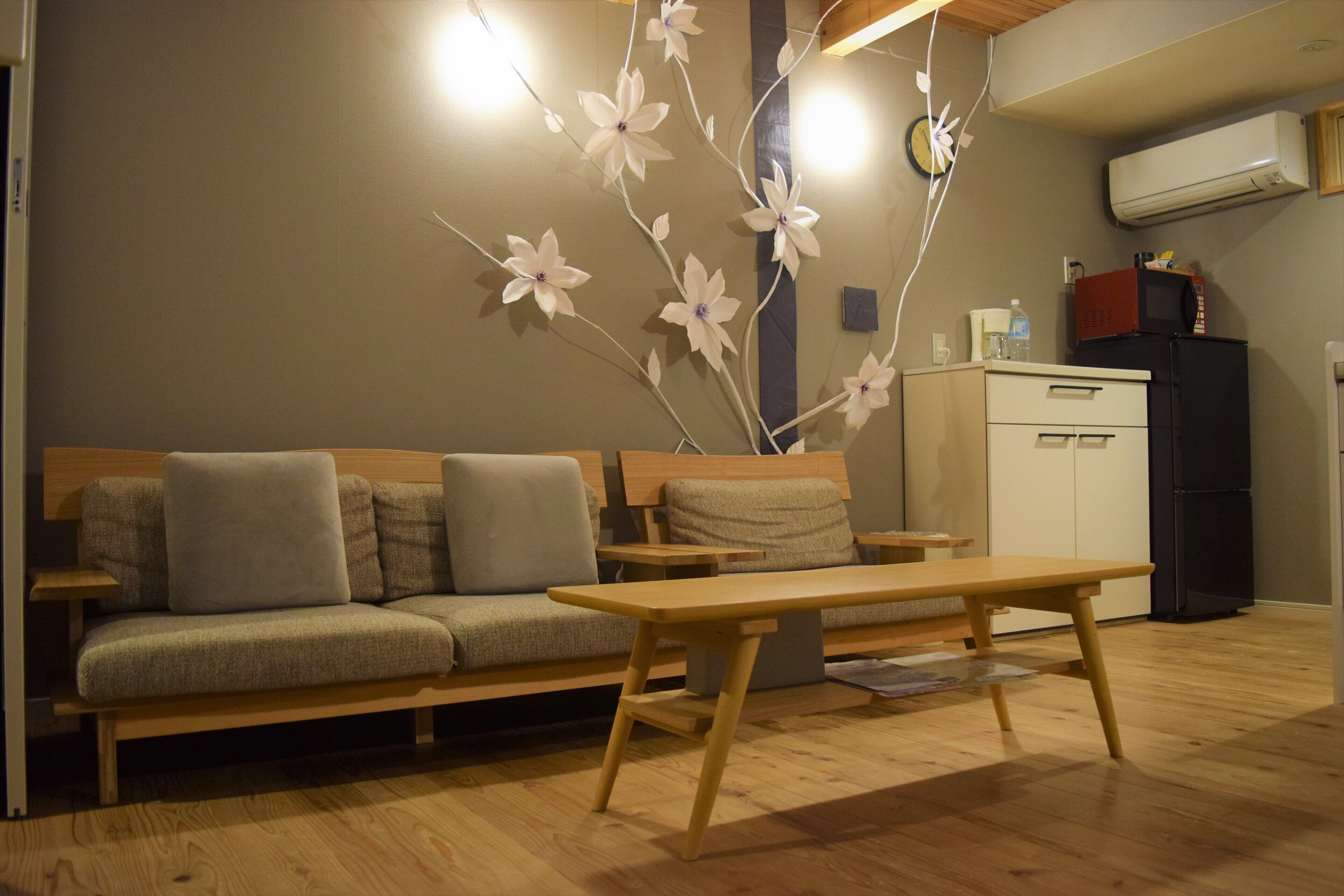 Una sala de estar con un sofá, una mesa de madera y una rama decorativa con flores.