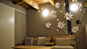A cozy room with a wooden bench, a small table, and a wall decorated with paper flowers. - Itomori (Takayama)