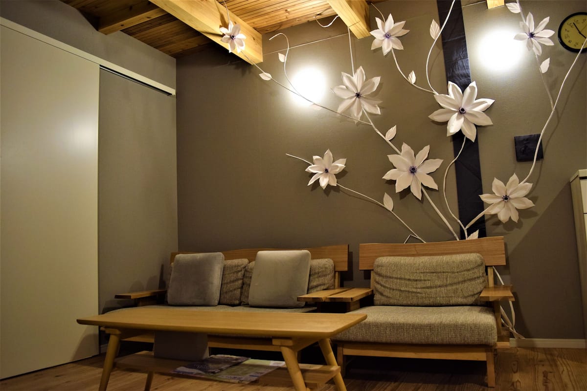 A cozy room with a wooden bench, a small table, and a wall decorated with paper flowers.
