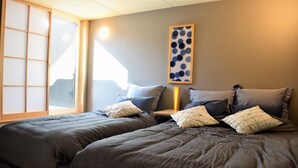 A bedroom with two beds, a shoji screen, a wall-mounted artwork, and a bedside table with a lamp. - Itomori (Takayama)