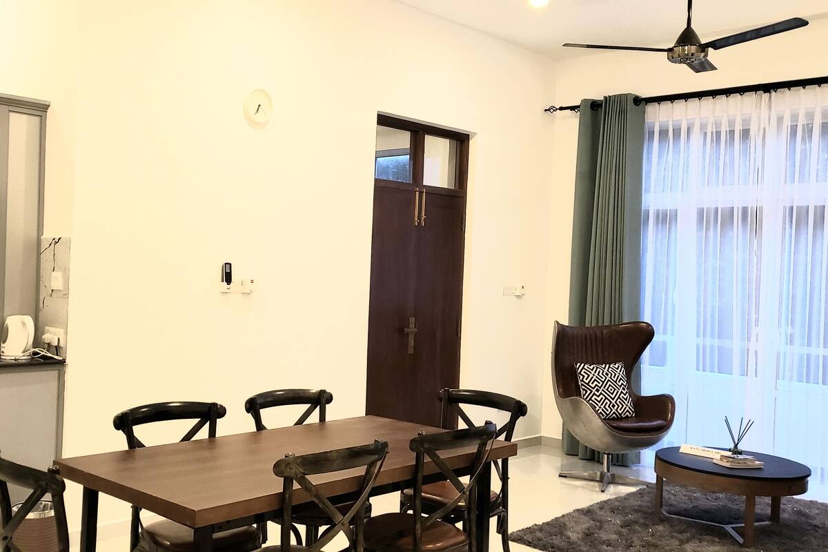 Un espacio habitable compacto con comedor, kitchenette y un amplio ventanal con cortinas.