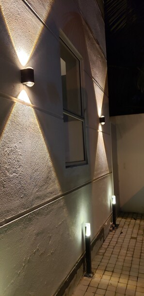 Une façade d’immeuble avec des murs à texture, une fenêtre et trois lampes fixées au mur.