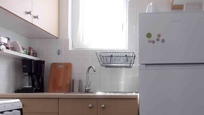 A compact kitchen with a window, a sink, a refrigerator, and a coffee maker. - Dervenion-Athens Cozy Apartment (Athens)