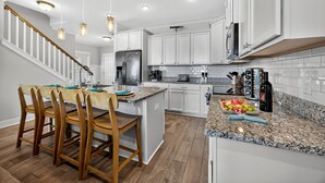 A modern kitchen with white cabinets, granite countertops, and a central island with seating. - Pet Friendly | Private Pool | Walk to Beach | Lagoon Views (Hilton Head Island)