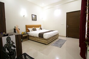 A bedroom with a wooden bed, a nightstand, a wall-mounted lamp, and a door. - The Hideout Agra Homestay (Agra)