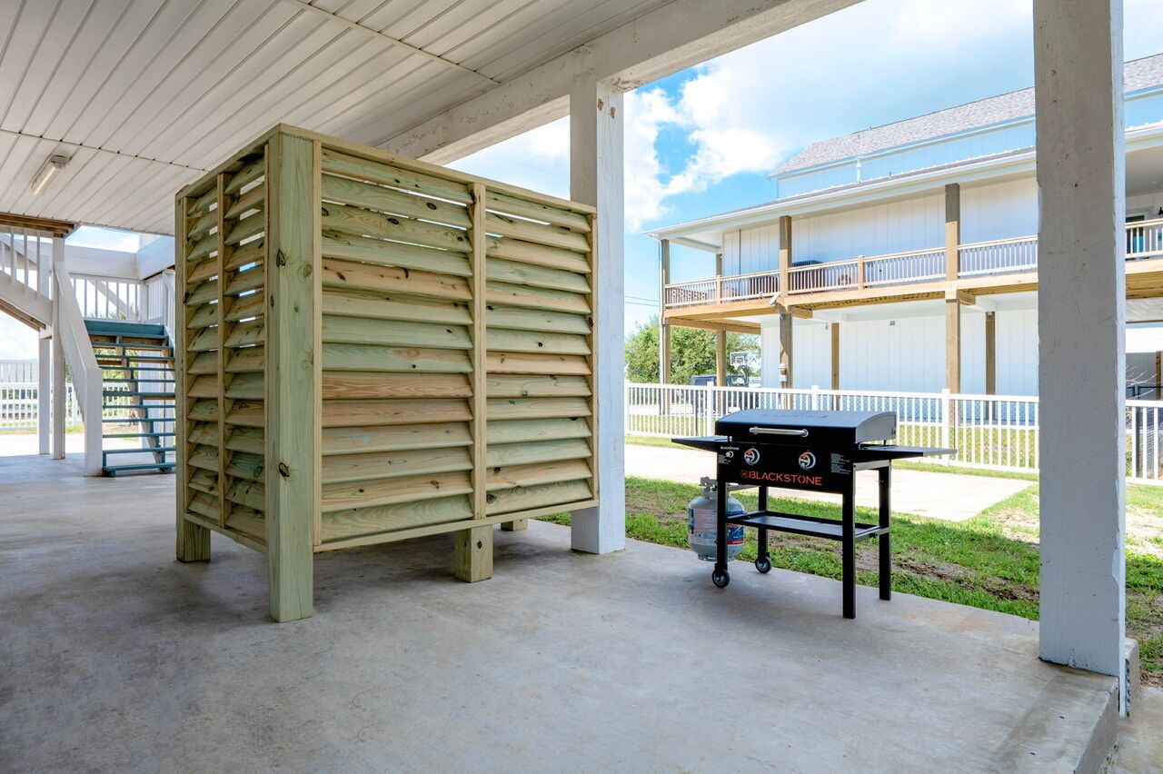 Un espacio al aire libre techado con una parrilla y una estructura de madera.