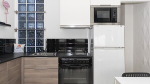 Une cuisine moderne avec un four noir, un four à micro-ondes et un réfrigérateur blanc.