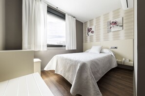 A modern bedroom with a bed, bedside table, and a window with curtains. - Hostal Residencia Victoria (Vedra)