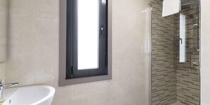 A bathroom with a white sink, a mirror, and a shower area with a tiled wall. - Hostal Residencia Victoria (Vedra)