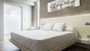 Ein modernes Schlafzimmer mit einem großen Bett, einem Nachttisch, einer Wandleuchte und einer Nachttischlampe.