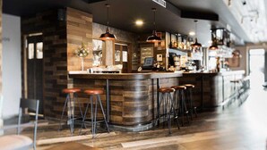 Eine Bar mit Holztresen, Hockstühlen, Pendelleuchten und einer sichtbaren Speisekarte.