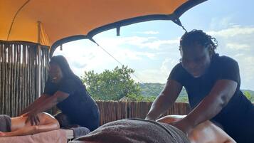 Eine Massageanwendung in einem Zelt mit Blick auf eine hügelige Landschaft.