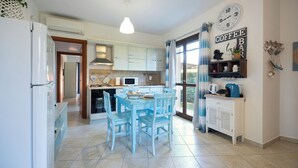 Una cocina con mesa, sillas, refrigerador, microondas y una barra para café.