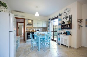 A kitchen with a dining table, chairs, a refrigerator, a microwave, and a coffee bar.