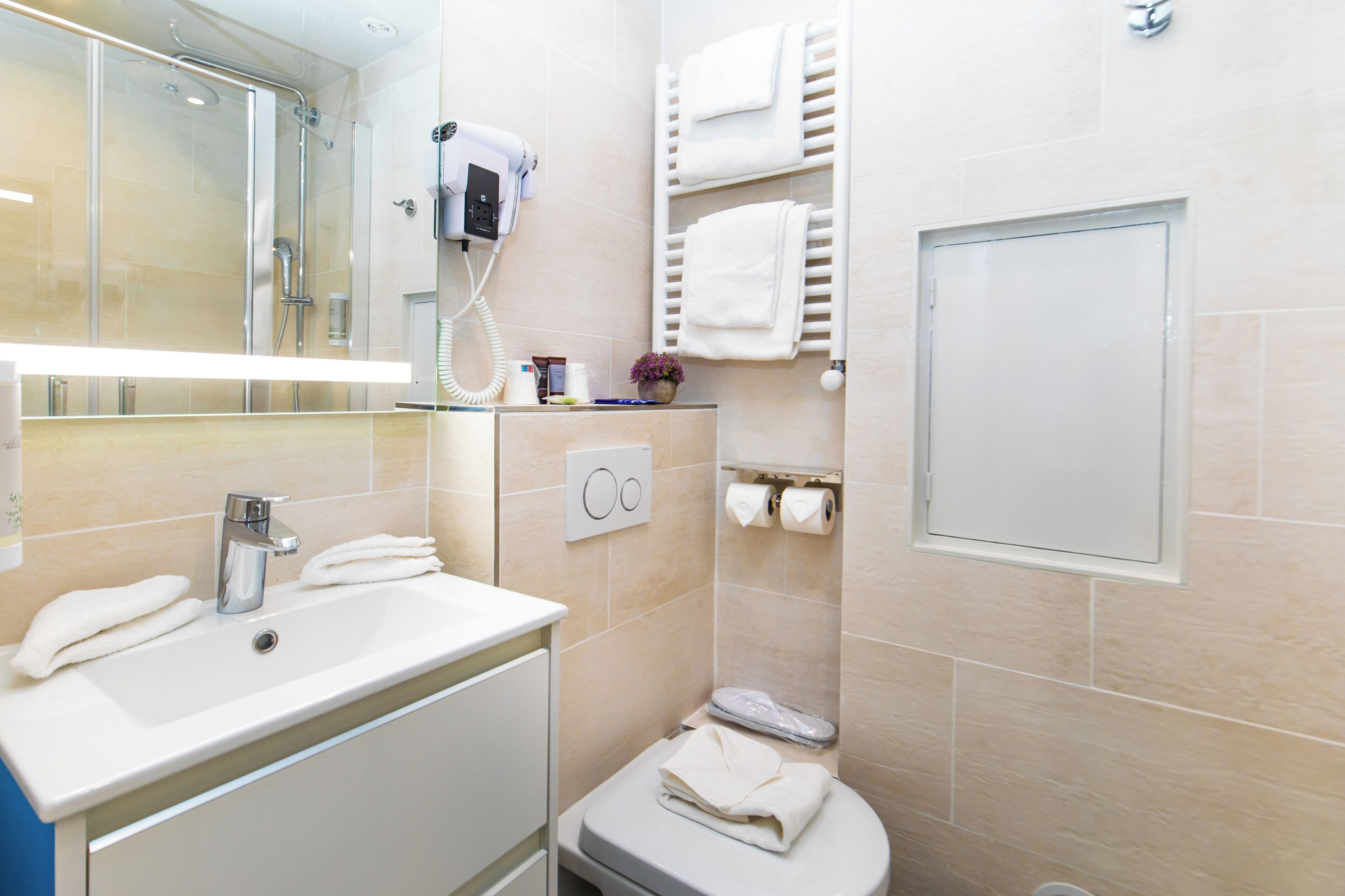 A modern bathroom with a sink, mirror, towel rack, and a toilet.