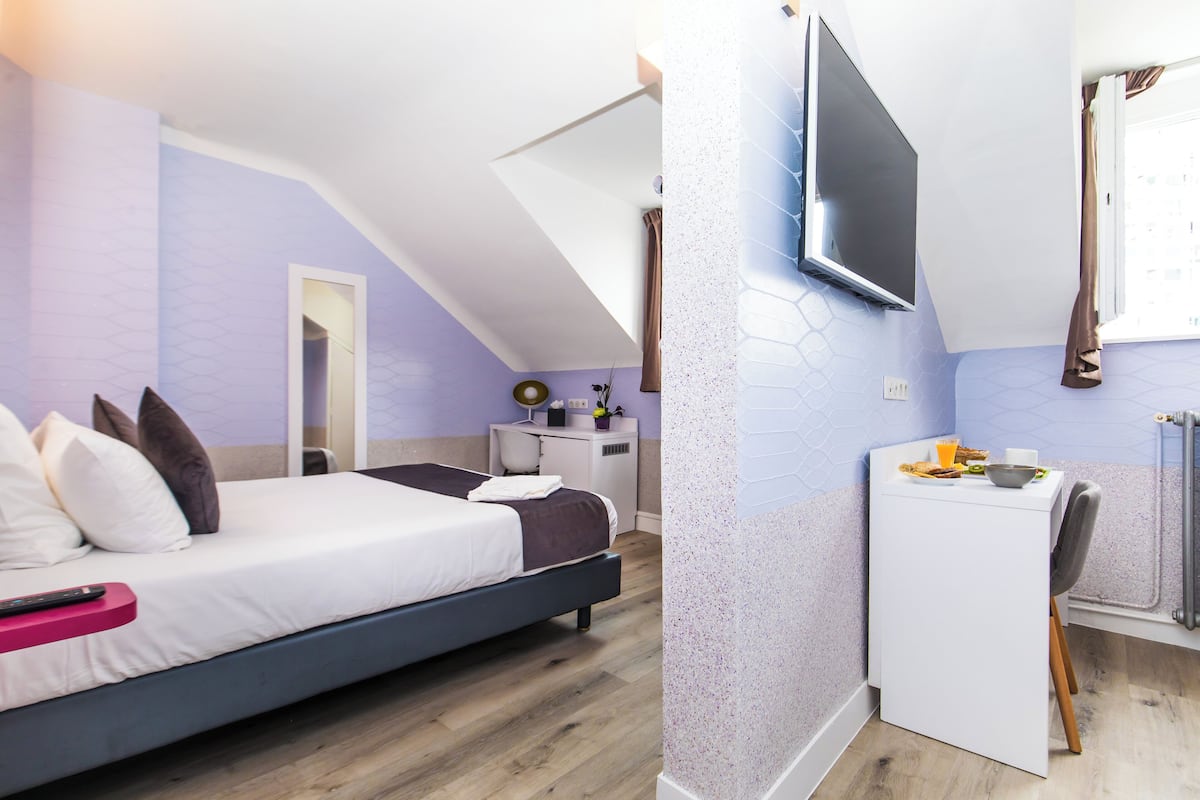 Une chambre à coucher avec un lit, un bureau et une télévision.