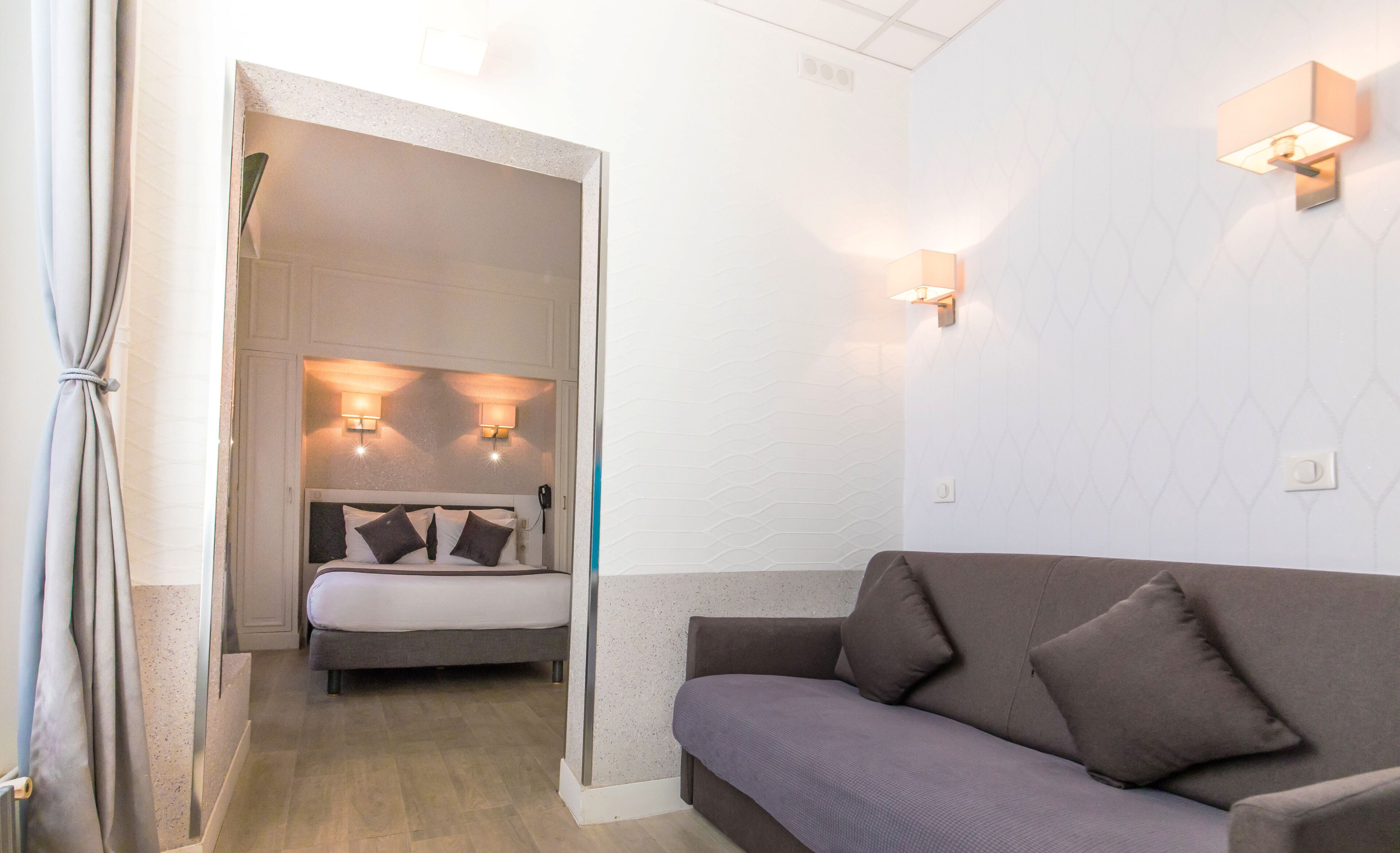 A room with a bed, a sofa, and two wall-mounted lights.