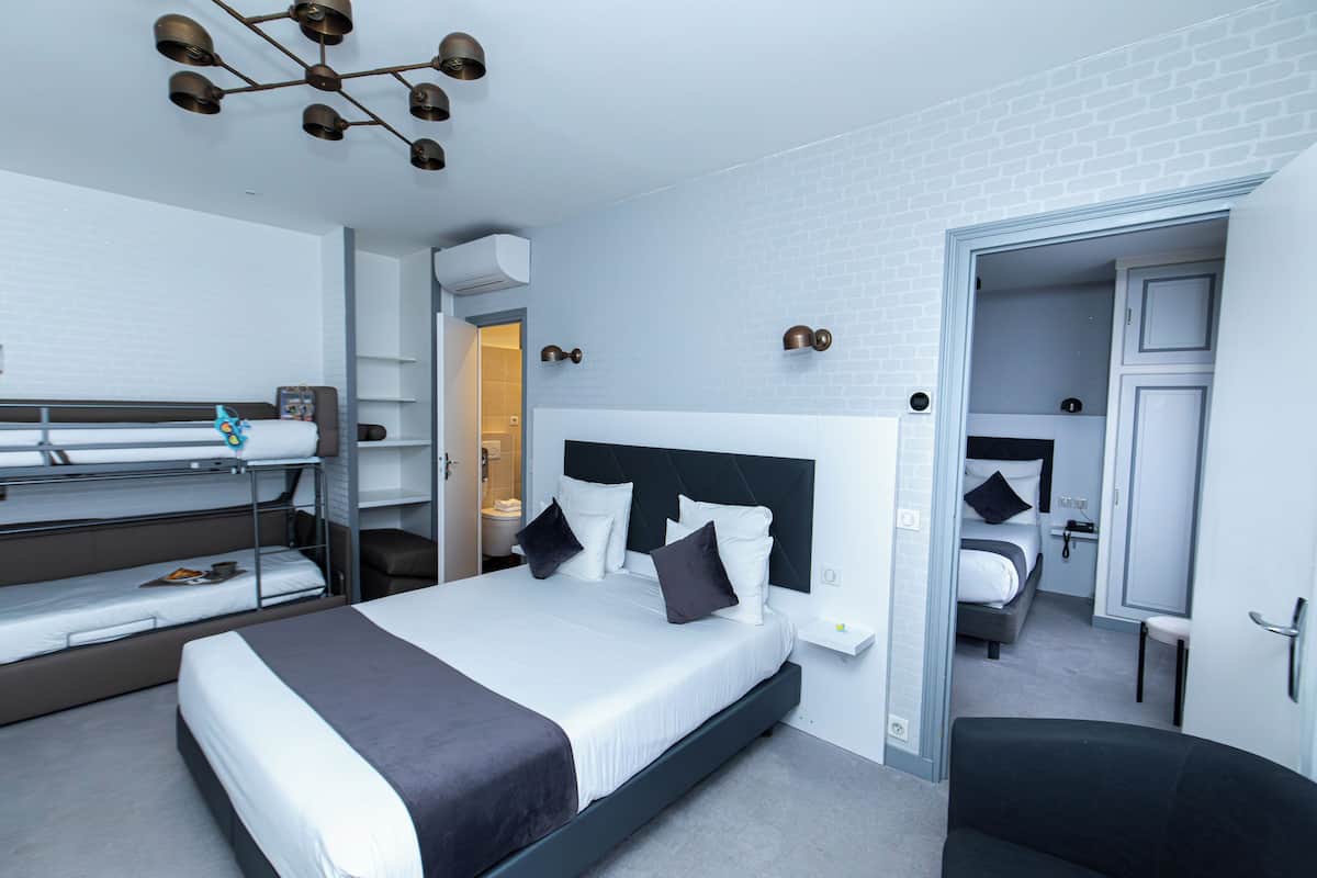 Une chambre d’hôtel moderne équipée d’un grand lit, de lits superposés, d’un bureau et d’une chaise.