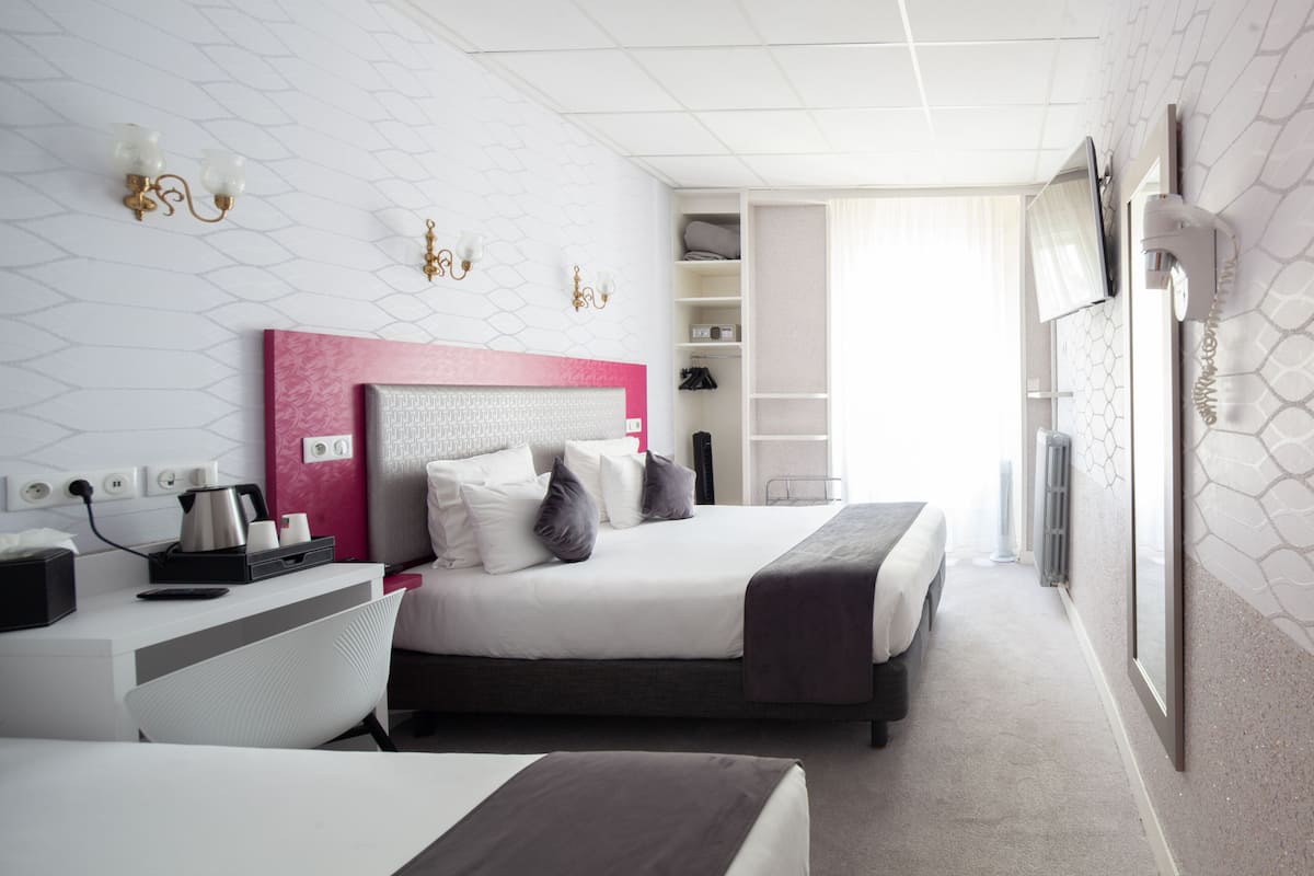 Une chambre d’hôtel moderne, dotée d’un grand lit, de tables de chevet, d’un bureau et d’une armoire.