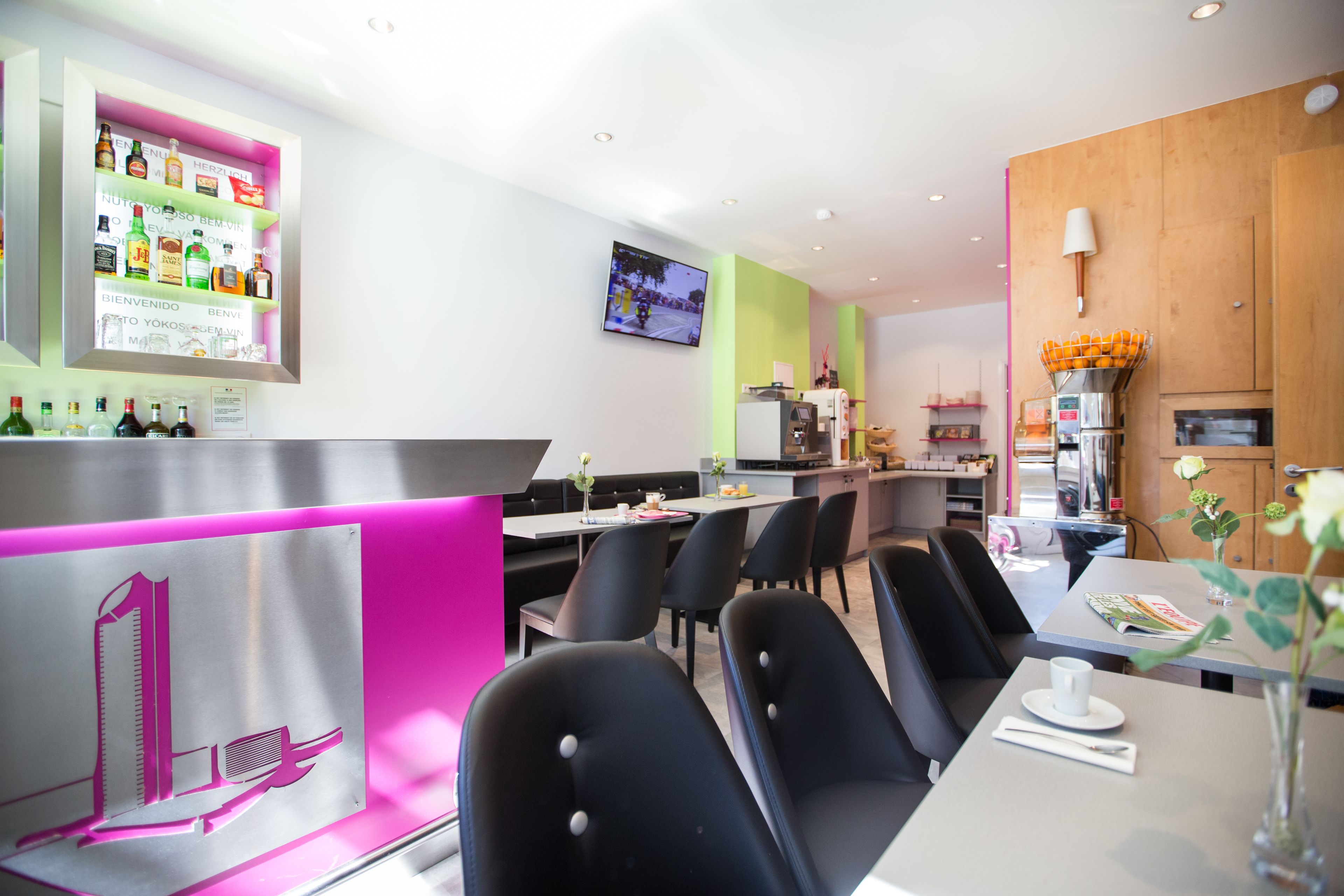 Un restaurante moderno con zona de bar, sillas negras y una pantalla de televisión.