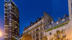 Une vue de rue de nuit, avec un hôtel appelé « HÔTEL DE PARIS » et une piste cyclable.