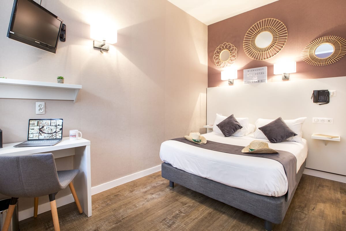 Une chambre d’hôtel moderne équipée d’un lit, d’un bureau et d’une télévision.