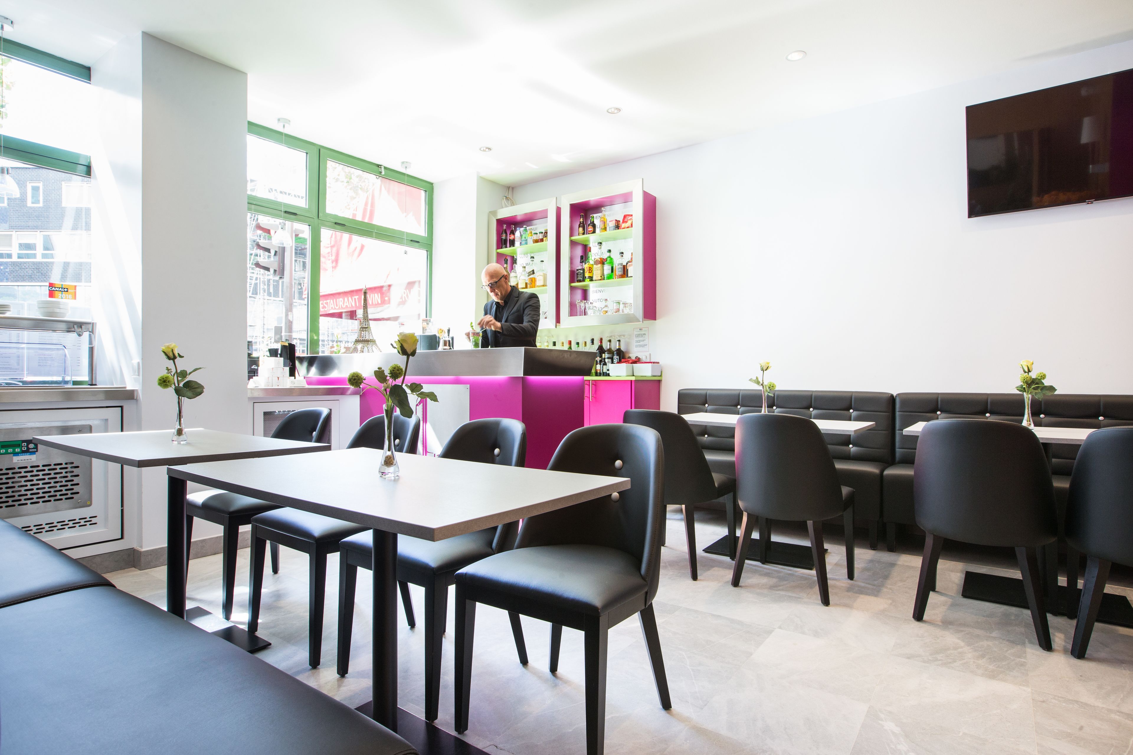Ein modernes Restaurant mit Bar, Sitzgelegenheiten und einem großen Fenster zur Straße.