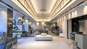Un moderno vestíbulo de hotel con una zona de estar central, una cocina y un comedor.