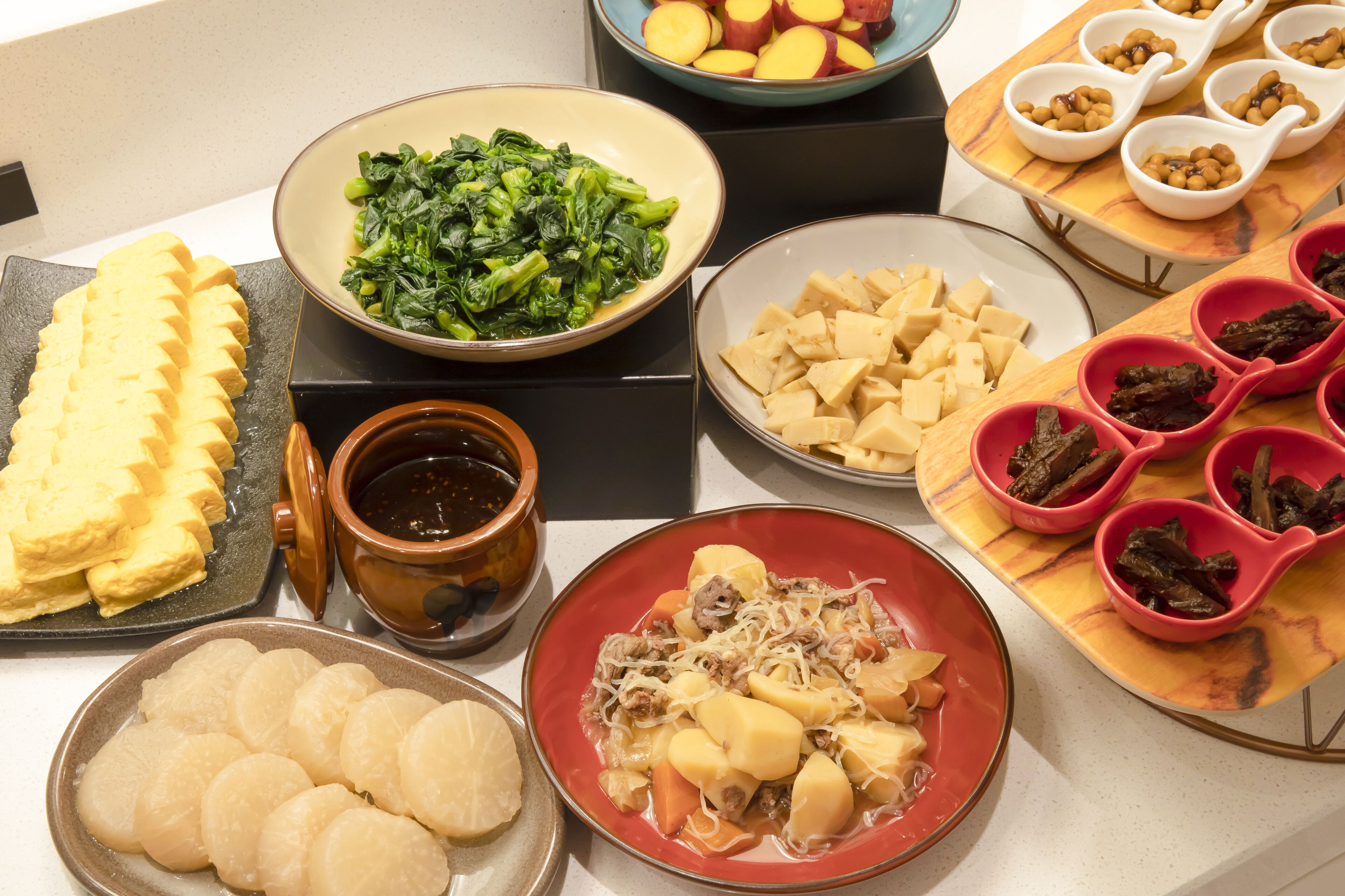 Una variedad de platos que incluyen tofu, verduras y carne, dispuesta sobre una mesa.