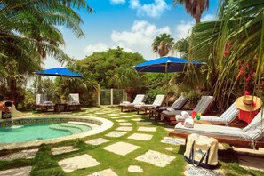 A poolside area with lounge chairs, umbrellas, and a swimming pool. - Hotel L'Esplanade (Grand Case)